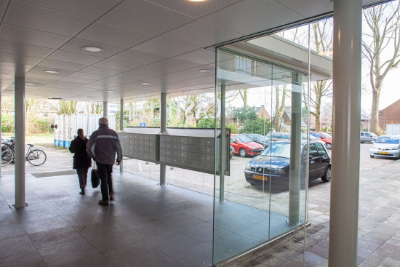 aangezicht van het vernieuwde entree vanuit de binnenkant gezien met twee bewoners van de flat castellum in leiden met veel glazen details