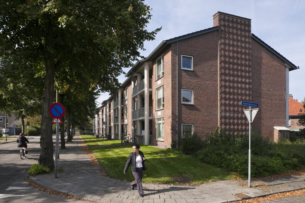 kopgevel van een van de gerenoveerde woonblokken aan de gasthuislaan in amersfoort met een fietser links en voor het gebouw een wandelaar