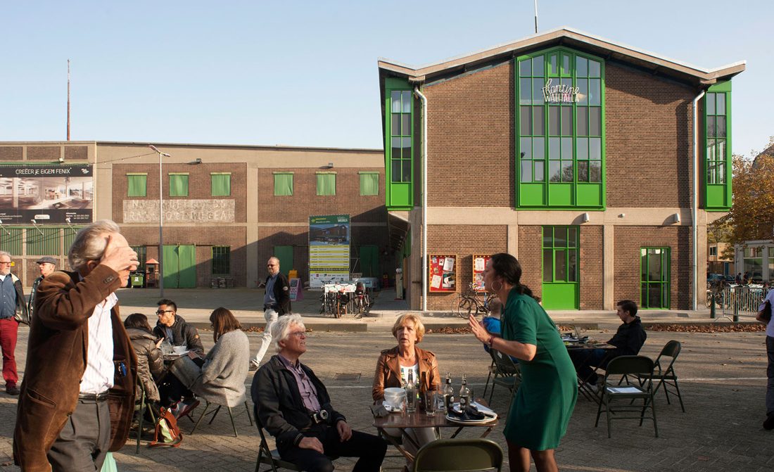 aanbeeld van op de achtergrond de kopgevel van de steinwegkantine en daarvoor een terras met mesnen die praten en lopen hoogwaardige en duurzame materialen