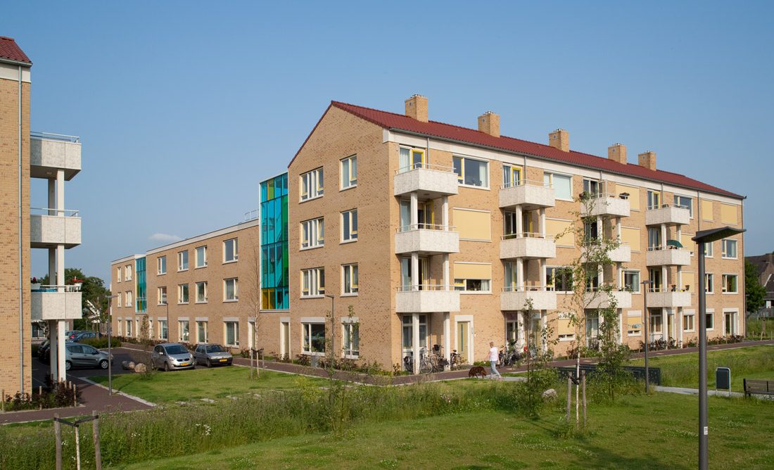 Zijaanzicht met uitstekende balkons van een van de gebouwen van de nieuwbouw in het schilderskwartier in woerden met gele en groene details