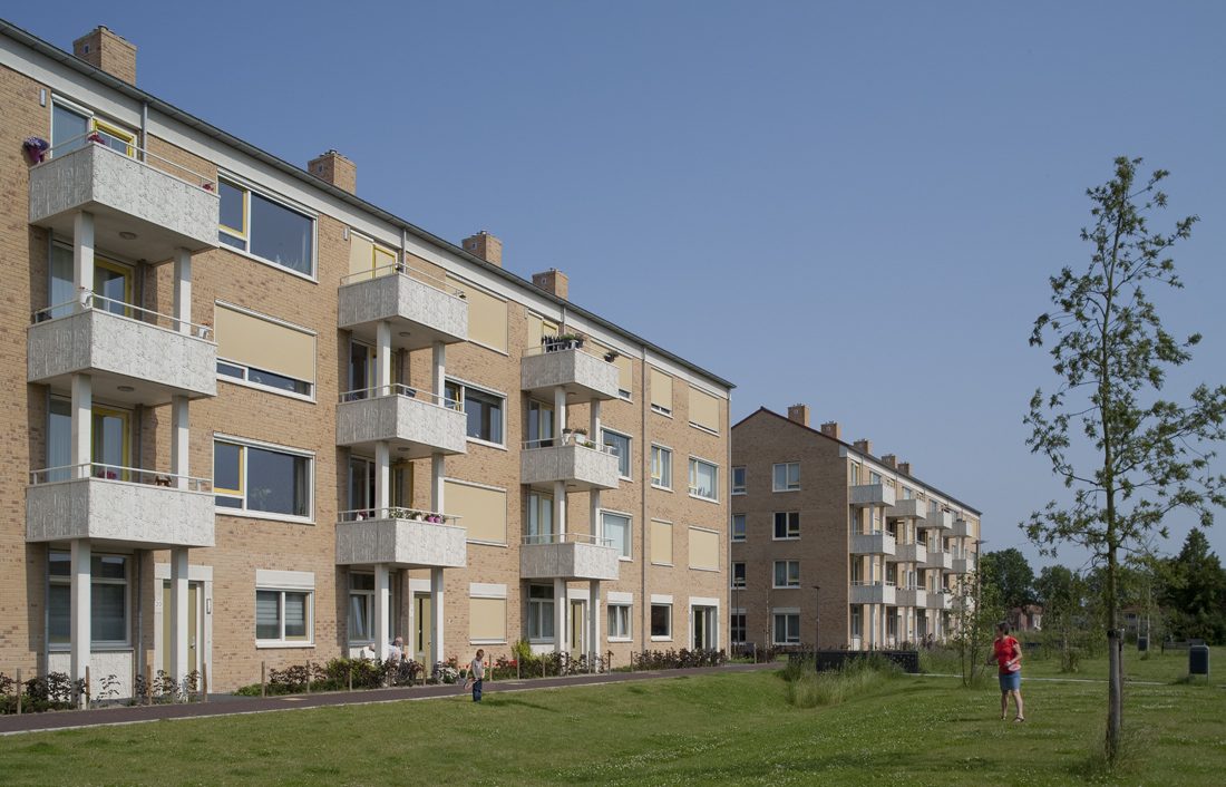 Zijaanzicht met uitstekende balkons van een van de gebouwen van de nieuwbouw in het schilderskwartier in woerden en mensen die spelen