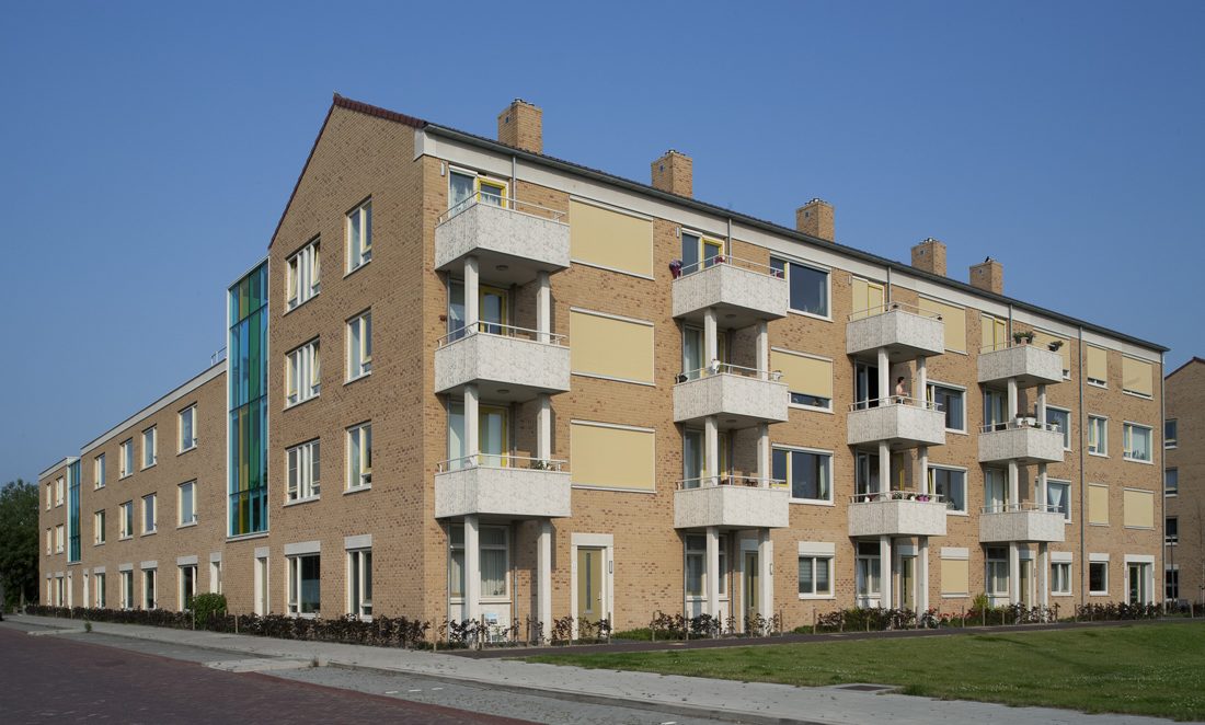 Zijaanzicht met uitstekende balkons van een van de gebouwen van de nieuwbouw in het schilderskwartier in woerden met gele en groene details