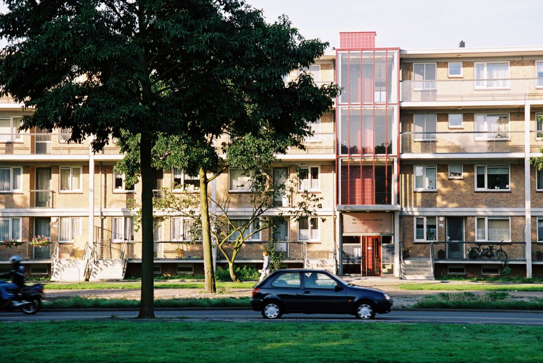 foto van de gerenoveerde portiek van de loevesteinlaan flat in het enschedelaan complex met een auto en gras op de voorgrond