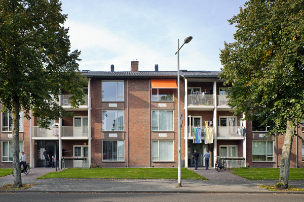 vooraanzicht van een van de gerenoveerde woonblokken aan de gasthuislaan in amersfoort met bewoners voor de entrees en was aan de balkons