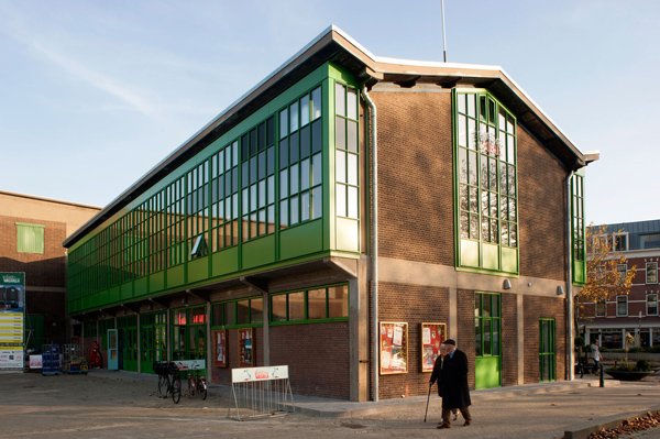 aanzicht van de kopgevel van de steinwegkantine in zijn nieuwe situatie na de renovatie op katendrecht rotterdam met een voetganger hoogwaardige en duurzame materialen