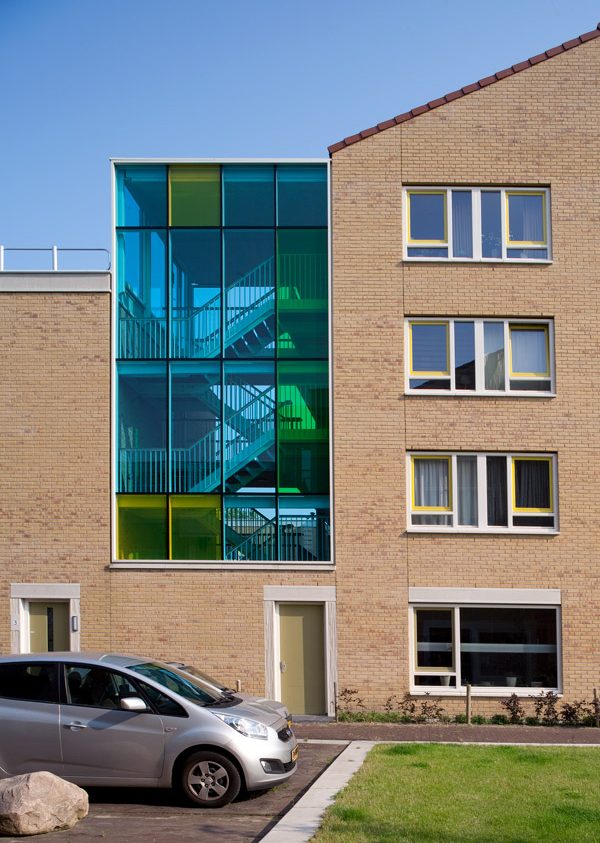 Aanzicht van de zijgevel balkons van een van de gebouwen van de nieuwbouw in het schilderskwartier in woerden met glazen wand in blauw, groen en geel