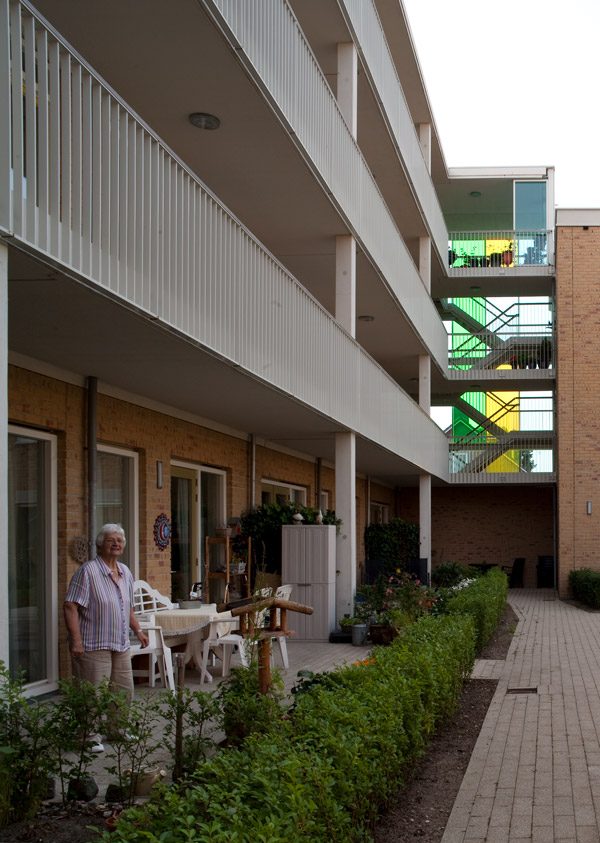 Aanzicht van de binnenplaats van een van de gebouwen van de nieuwbouw in het schilderskwartier in woerden met gele, groene en blauwe glazen wand