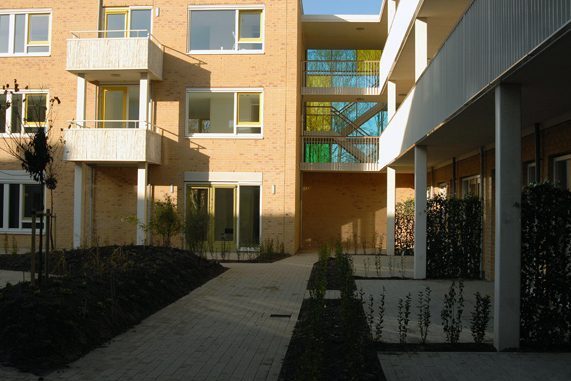 Aanzicht van de binnenplaats van een van de gebouwen van de nieuwbouw in het schilderskwartier in woerden met gele, groene en blauwe glazen wand