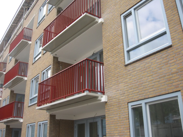 foto van een fragment van de gerenoveerde dudokhaken met de vernieuwde rode balkons na de renovatie in geuzenveld in amsterdam