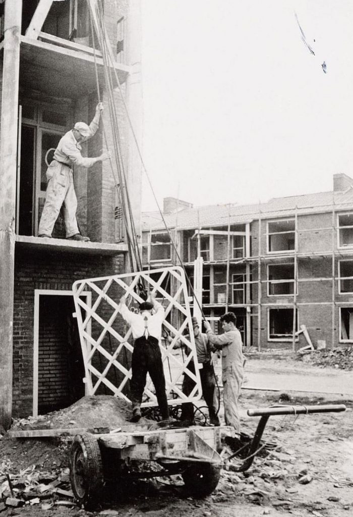 oud beeld van mannen die ene van de balkonplaten naar boven takelen aan een van de nieuwbouw woonblokken aan de gasthuislaan in amersfoort