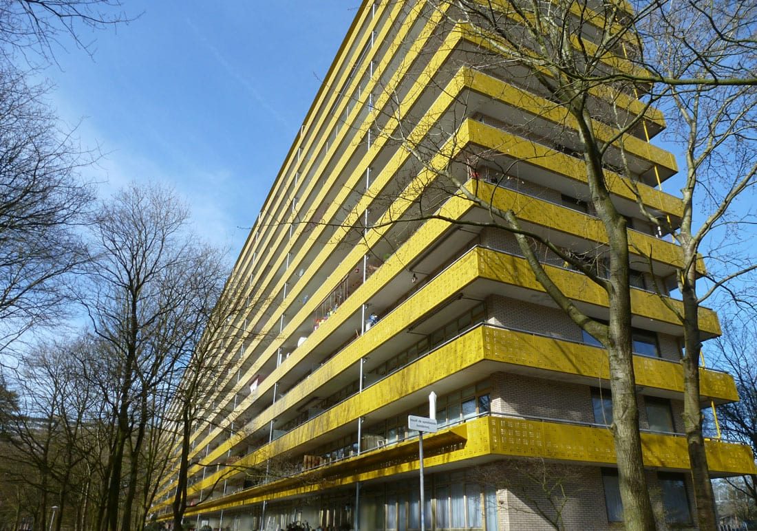 foto van de geroflat na de renovatie in zeist met gele balkons en bomen om het gebouw heen het autonome, krachtige beeld