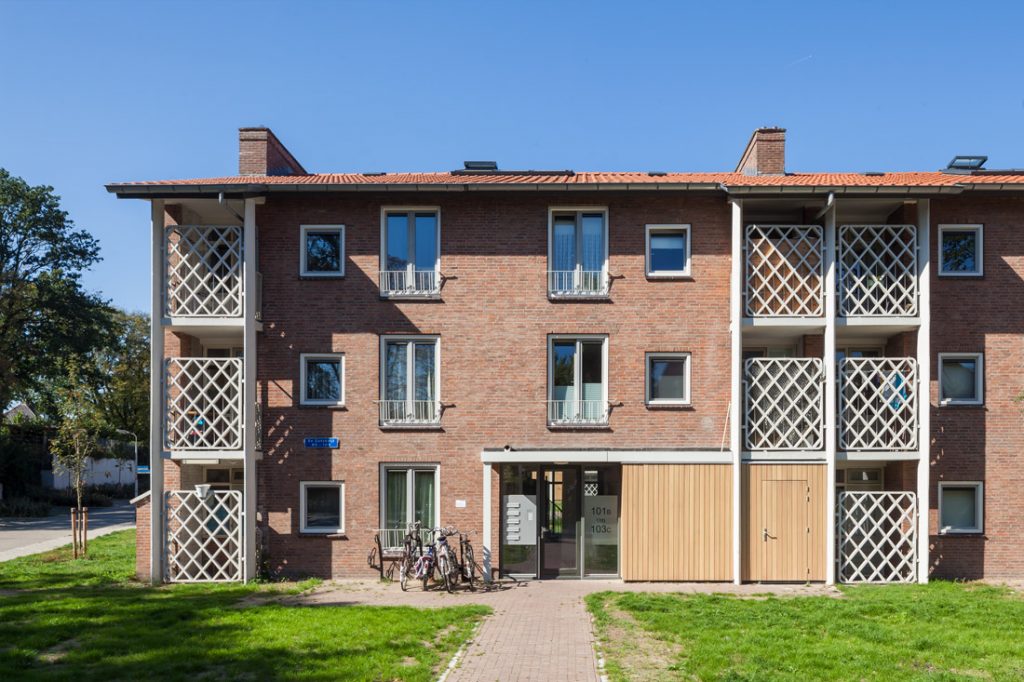 vooraanzicht van een van de gerenoveerde woninggebouwen in de wijk de ganskuijl in amersfoort met yperende witte geruite geperforeerde hekken als balkons