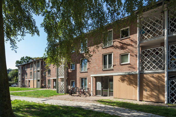 zijaanzicht van een van de gerenoveerde gebouwen in de ganskuijl in amersfoort met veel begroeiing in de omgeving en fietsen voor de entree