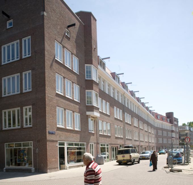 Zijaanzicht van links aan de voorkant van het gerenoveerde appartementencomplex in de Gorontalostraat in Amsterdam met personen op de voorgrond