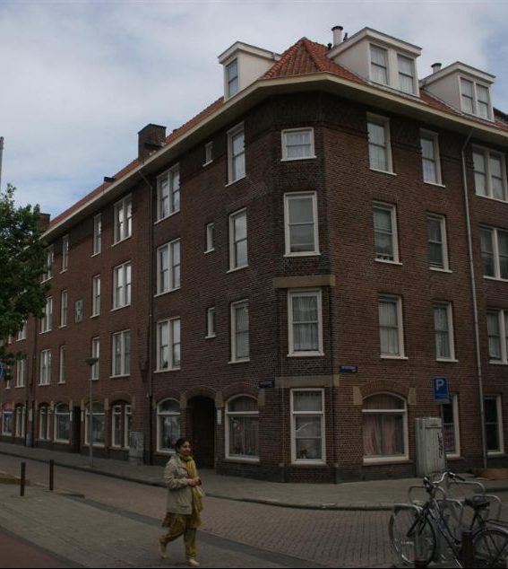 de huizen aan de hoek van de tugelaweg in de bestaande situatie voor de renovatie met een wijkbewoner lopend over de stoep