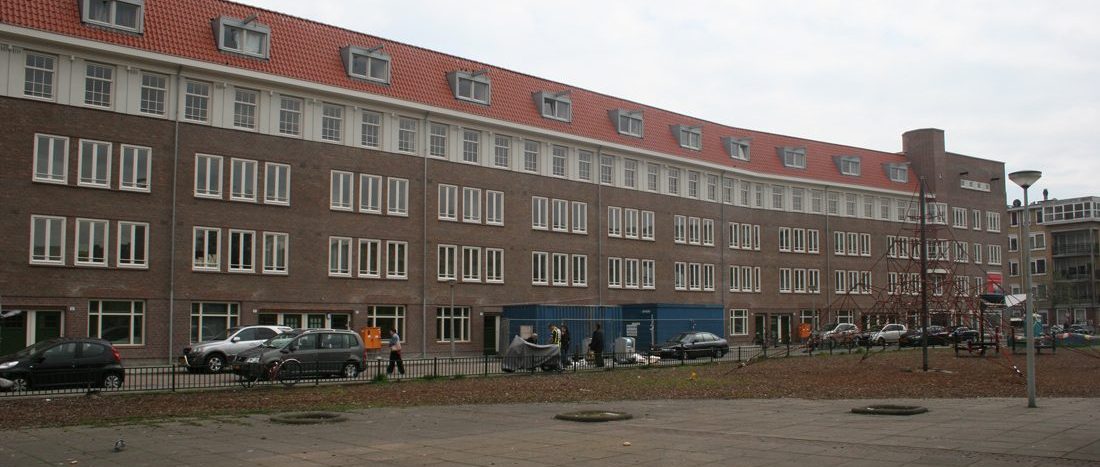 Compleet aanzicht van de voorkant van het gerenoveerde appartementencomplex in de Gorontalostraat in Amsterdam met speeltuin